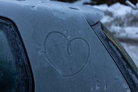 heart symbol on frozen grey car body in winterの写真素材