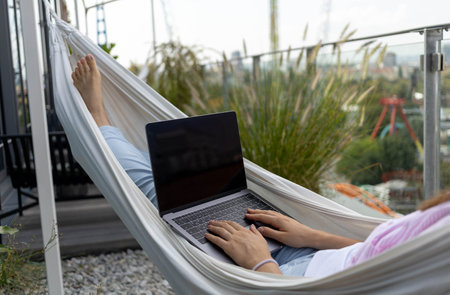 young woman freelancer working in hammock on terraceの写真素材