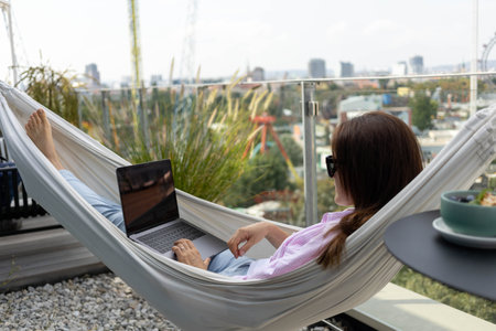 young woman freelancer working in hammock on terraceの写真素材