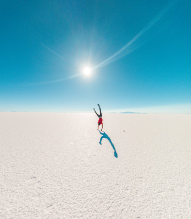 Back of a boy doing cart wheels at Uyuni salt flats in Bolivia. Sunflareの写真素材
