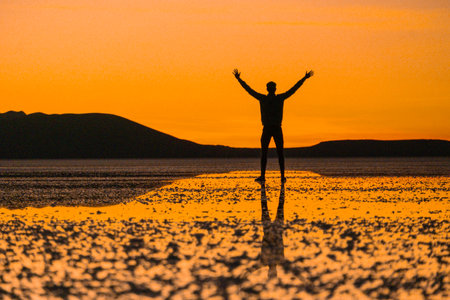 Sunset at Uyuni salt flats with reflection of happy personの写真素材