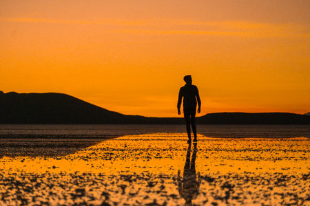 Sunset at Uyuni salt flats with human reflectionの写真素材