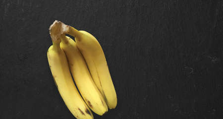 Top up view isolated fresh yellow bananas isolated on dark table. added copy space for text.の写真素材
