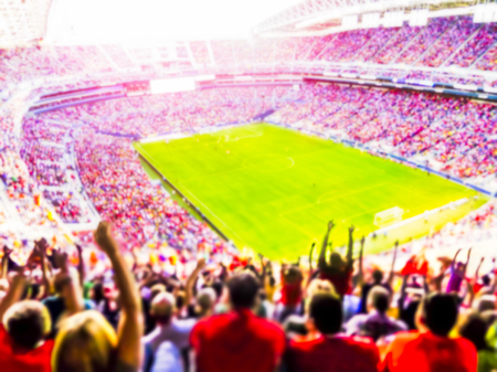 Football- soccer fans cheer their team and celebrate goal in full stadium with open air  with bright lighting beam     -blurred.の写真素材