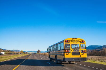 school bus running on the road against the blue sky.の写真素材