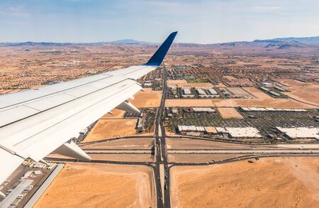 airplane wing over the desert city on sunny day.