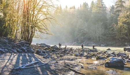 people in river with ice and snow in the morning.