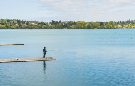 a man fihing in the blue lake  in the  park.の写真素材
