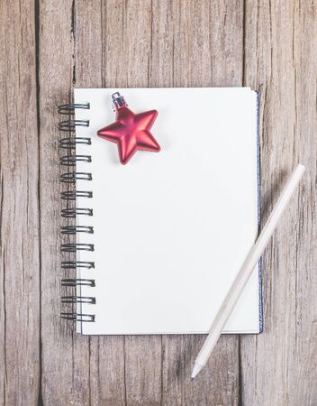white blank space notebook with pencil and christmas ornament on the wooden top.の写真素材