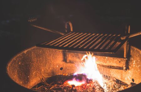 Stainless Steel BBQ Grill over bonfire im camp site in campground at night.の写真素材