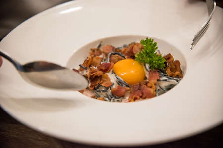 Black carbonara spaghetti with egg and baconの写真素材