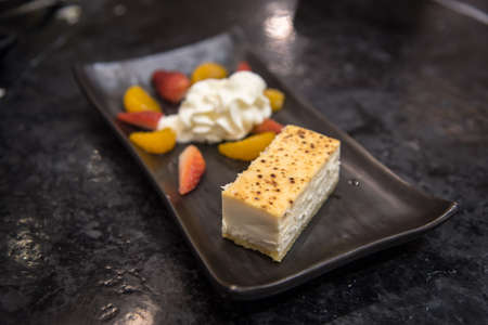 Cheesecake with orange and strawberry whip cream on the plate