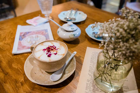 latte art coffee with spoon on wooden table, Top with dry flower for decoration.の写真素材