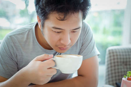 drinking coffee by asian man in grey shirt.の写真素材