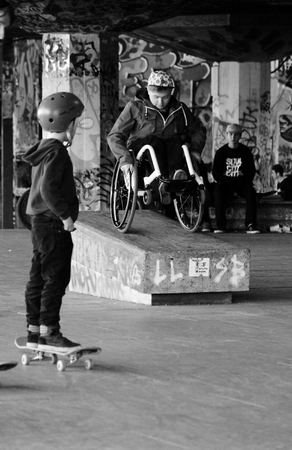 Man in a wheelchair doing stunts on ramp child watchesのeditorial素材