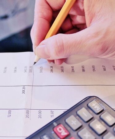 Financial data analyzing accounting with pencil and calculatorの写真素材