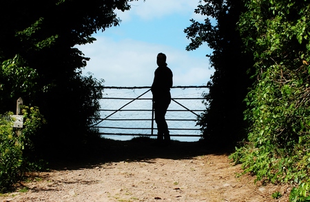 silhouette of man by farm country gate looking at viewの写真素材