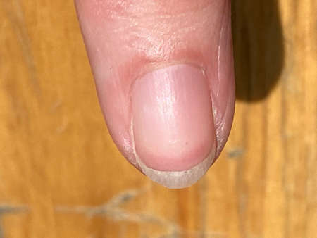 A closeup shot of a female fingernail with a blurred background