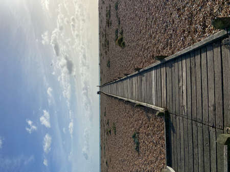 A low angle shot of a wooden fence on a beach under a blue skyの写真素材