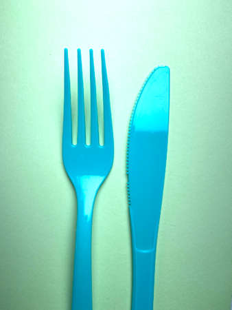 Blue plastic cutlery, fork and knife on green background.の写真素材
