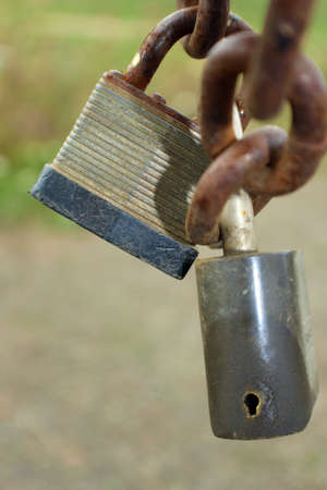 Two padlocks hanging from a rusty chain
