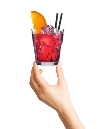 Woman hand holding cocktail in old fashioned glass with ice cubes and black straw on whiteの写真素材
