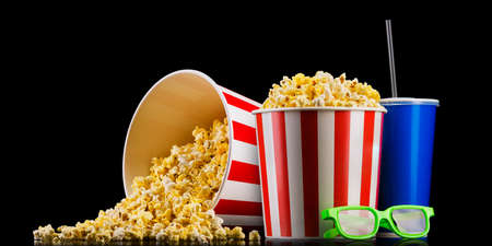 Paper striped bucket with popcorn, cup of soft and glasses isolated on blackの写真素材