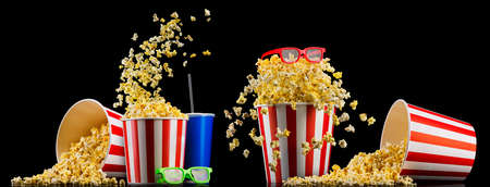 Paper striped bucket with popcorn, cup of soft and glasses isolated on blackの写真素材