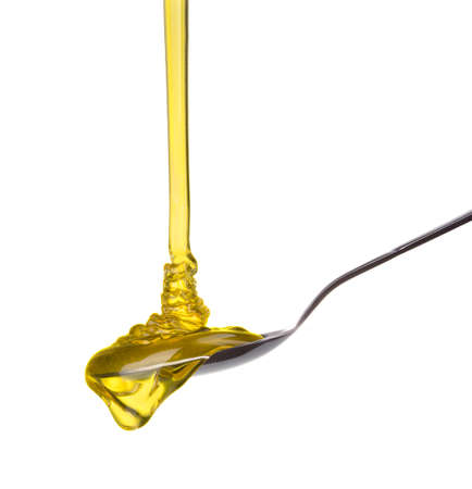 Falling and flowing honey on a spoon isolated on whiteの写真素材