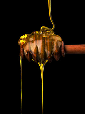 Honey on a wooden dipper isolated on blackの写真素材