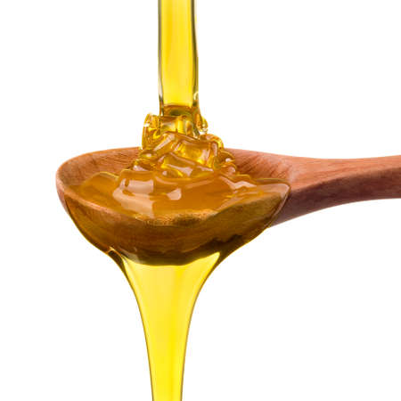 Falling and flowing honey on a wooden spoon isolated on white background with clipping path.の写真素材