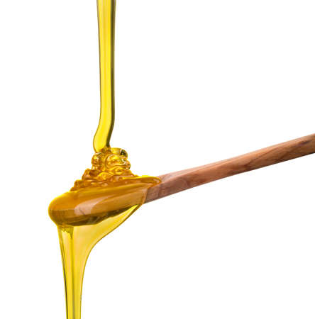 Falling and flowing honey on a wooden spoon isolated on white background with clipping path.の写真素材