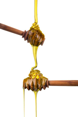 Set of wooden spoon with falling and flowing honey on them isolated on whiteの写真素材