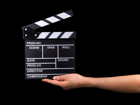Human hand holding fiilm clapper board  on black background   .