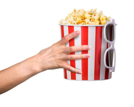 Woman hand holding striped bucket with popcorn and 3D glasses isolated on whiteの写真素材