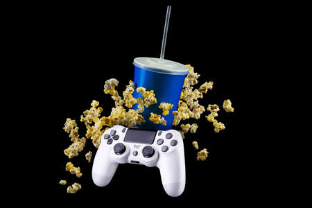 Blue cup with cap and flying popcorn isolated on black background. Concept of refreshments in cinema...
