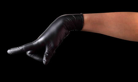 Hand in black gloves with the index finger pointing or touching something isolated on black...
