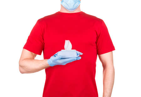 Man in red t-shirt, medical mask and gloves holding wet wipes or tissue isolated white background with clipping path. Concept of hygiene and protection from Covid-19 on workの写真素材