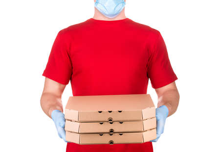 Delivery man in red t-shirt and blue medical gloves holding pizza boxes isolated white background...