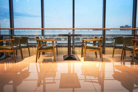 Tables and chairs in front of floor-to-ceiling windows in a shopping mall coffee shopのeditorial素材