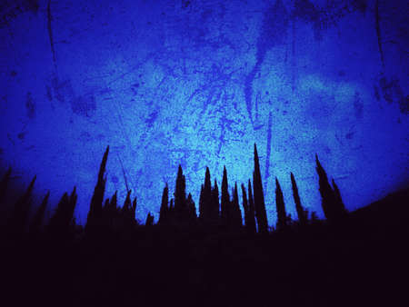 Grunge blue background and silhouette of treesの写真素材