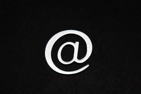 Silver 3D email sign against a black backgroundの写真素材