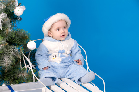 baby in blue Santa Claus hat near Christmas treeの写真素材