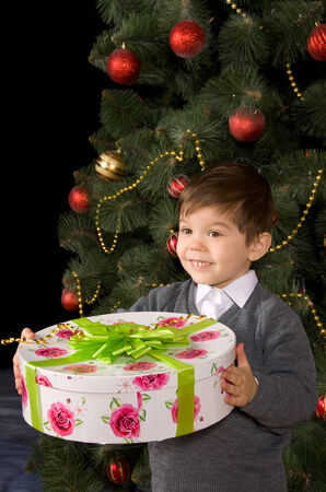 Happy boy with gift in their hands near  Christmas treeの写真素材