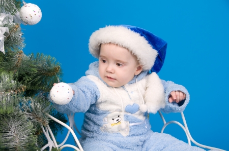 baby in blue Santa Claus hat near Christmas treeの写真素材
