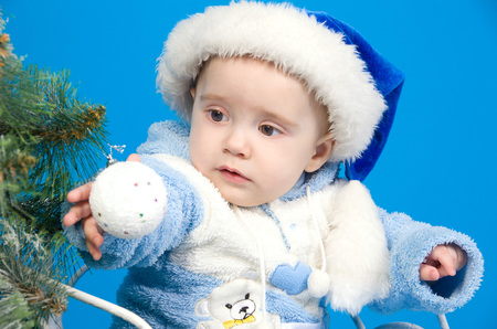 baby in blue Santa Claus hat near Christmas treeの写真素材