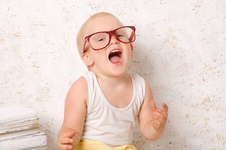 Boy in red glasses on the background of wooden white painted wallsの写真素材