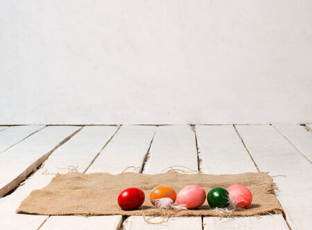 Easter colored eggs lie on canvas on wooden white floorの写真素材
