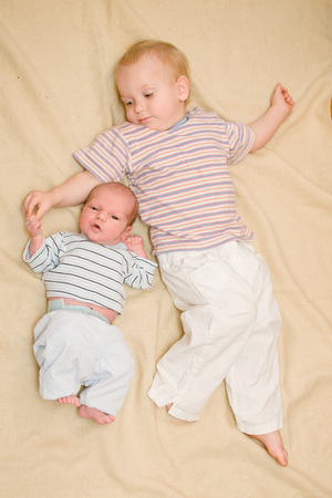 brothers lie on your back on a beige background, and holding handsの写真素材