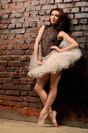 ballerina in tutu on tiptoe near old brick wallの写真素材